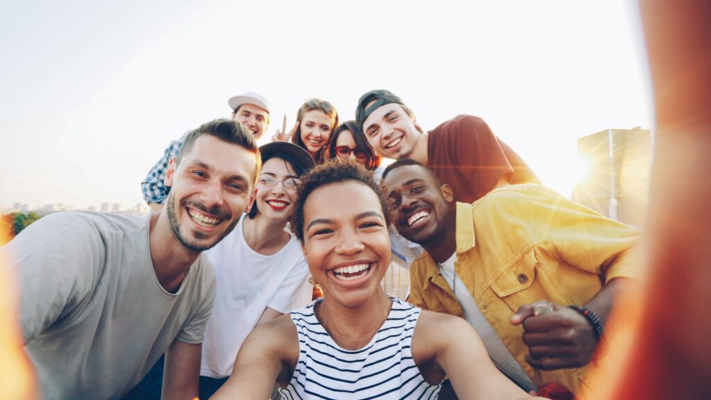 A diverse group of friends taking a joyful selfie outdoors during sunset.